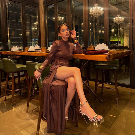 Alina Statement Slit Cut Maxi Dress In Brown - full-length seated shot on model at a restaurant table - Miss Mosa By Akanksha