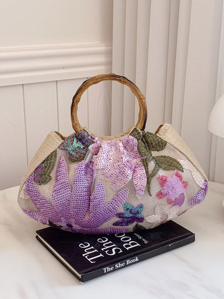 Dabel Embroidered Hand Bag - angled shot styled on a book, beige with lilac and pink floral sequins - Miss Mosa By Akanksha