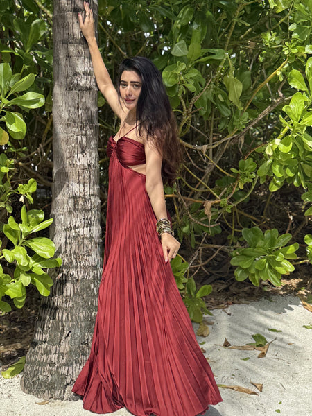 Hay Luxe Pleated Flowy Maxi Dress In Maroon - full-length side shot on model beside a palm trunk - Miss Mosa By Akanksha