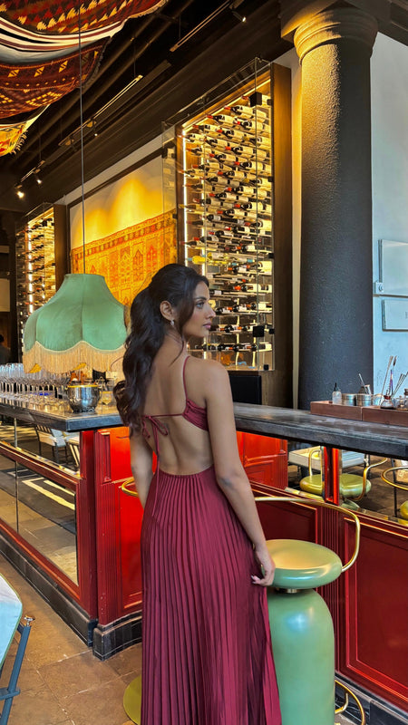 Hay Luxe Pleated Flowy Maxi Dress In Maroon - back shot on model at a bar - Miss Mosa By Akanksha