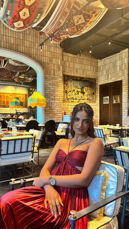 Hay Luxe Pleated Flowy Maxi Dress In Maroon - seated front shot on model at a restaurant - Miss Mosa By Akanksha