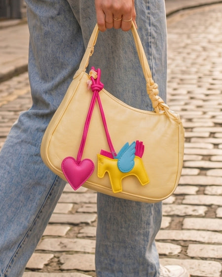 Horse and Heart Set of 2 Bag Charms - lifestyle shot of charms on yellow bag held by model, pink and yellow - Miss Mosa By Akanksha
