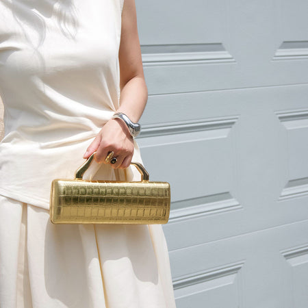 Leif Hand Bag With Chain - handheld shot on model outdoors, gold - Miss Mosa By Akanksha